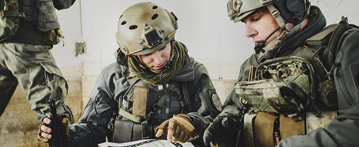 Soldiers consult paperwork in the field