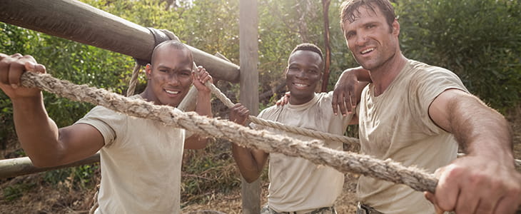 Cadets pause on an obstacle course and smile